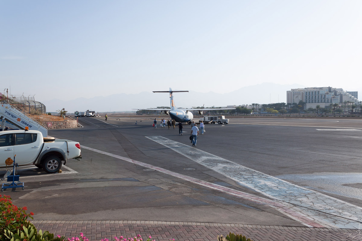 Люди идут пешком по лётному полю аэропорта в Эйлате