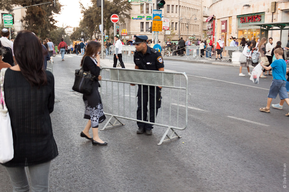 Девушка в Иерусалиме что-то спрашивает у мента, несущего ограждение