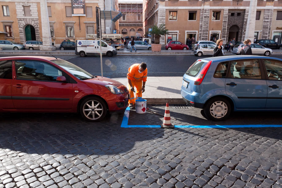 Рабочий в Риме наносит разметку с обозначение стоянки