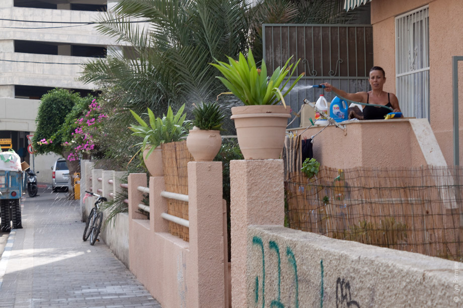 Женщина в Тель-Авиве поливает какую-то траву